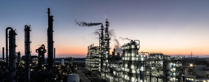 Torres e tubulações de uma planta química iluminadas ao entardecer