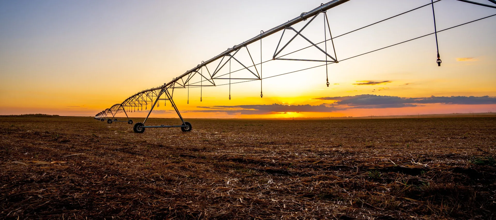 Sistema de irrigação por pivô em área agrícola ao pôr do sol, em fotografia institucional da BrasilAgro