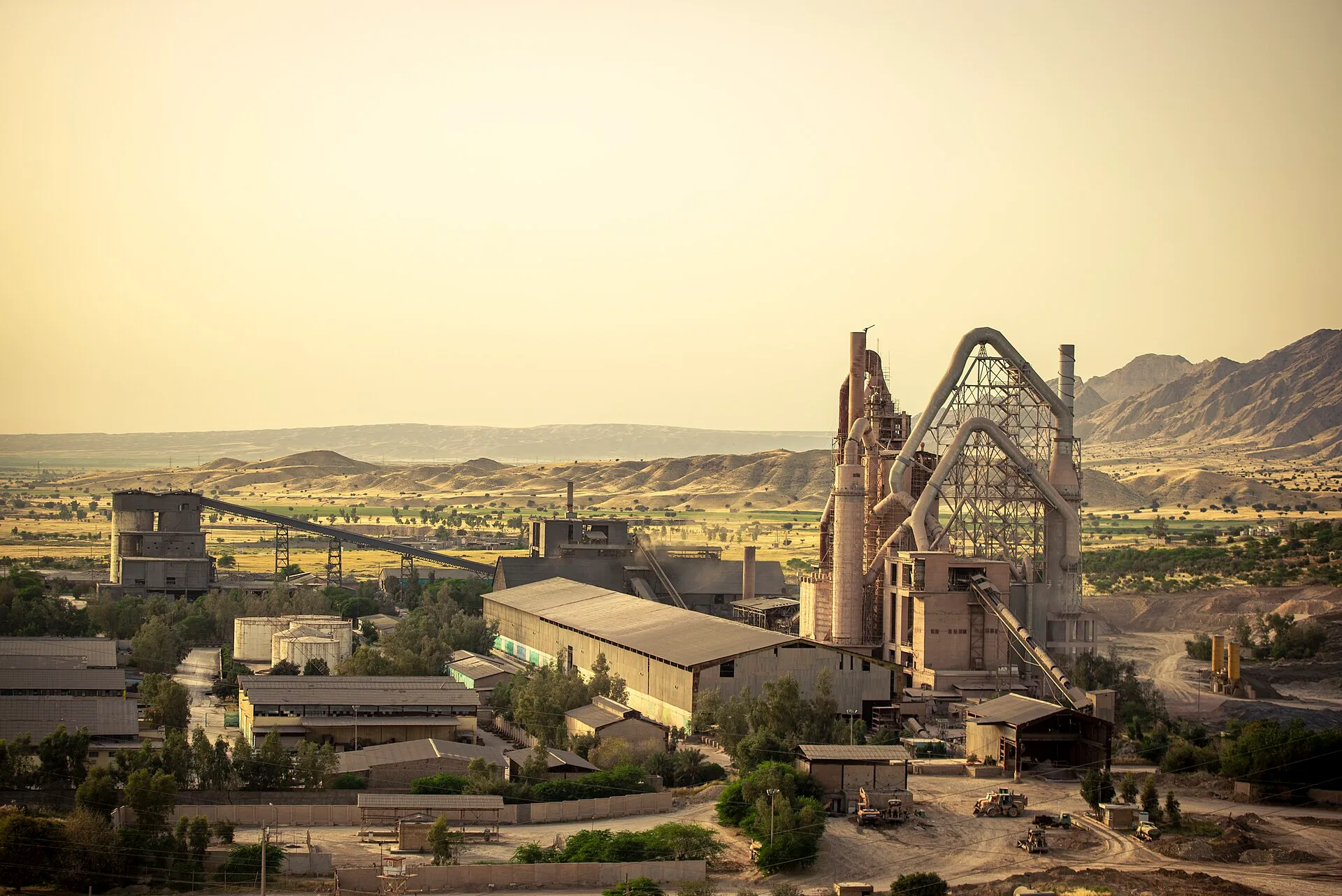 Fábrica de cimento em Behbahan, Irã, com torres de processo, transportadores, silos e galpões