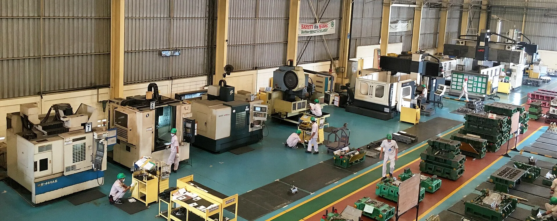 Galpão industrial com fileiras de máquinas de usinagem e áreas de circulação
