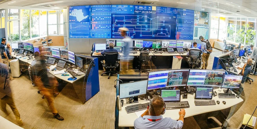 Profissionais no Centro de Operação de Transmissão da ISA Energia Brasil, diante dos painéis e estações de monitoramento